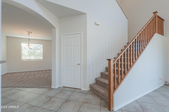 stairway featuring tile patterned floors and a notable chandelier