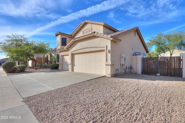 view of front facade featuring a tiled roof, fence, concrete driveway, and stucco siding