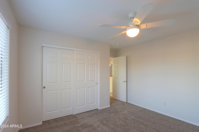 unfurnished bedroom featuring carpet floors, a closet, and ceiling fan