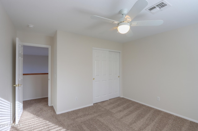 unfurnished bedroom featuring a closet, light colored carpet, and ceiling fan