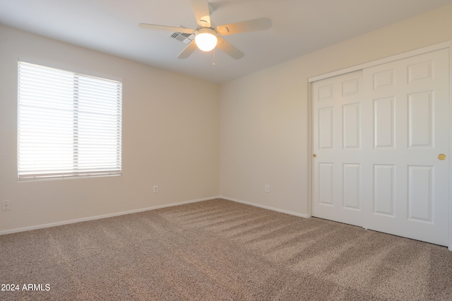 unfurnished bedroom featuring carpet floors, a closet, and ceiling fan