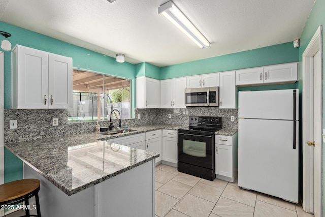 4624 S Fair Ln, Tempe, AZ 85282 - kitchen with freestanding refrigerator, stainless steel microwave, electric range, a sink, and a peninsula