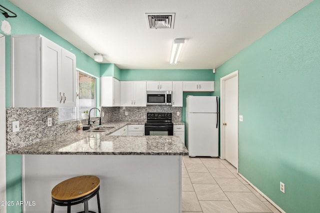 4624 S Fair Ln, Tempe, AZ 85282 - kitchen with stainless steel microwave, freestanding refrigerator, black range with electric cooktop, a sink, and light stone countertops