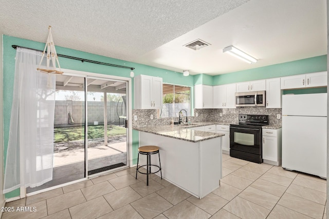 4624 S Fair Ln, Tempe, AZ 85282 - kitchen with freestanding refrigerator, stainless steel microwave, black / electric stove, a sink, and white cabinets