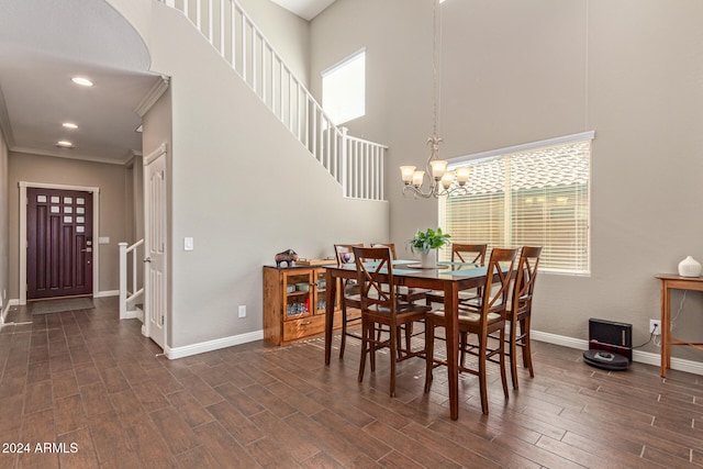 dining area featuring a high ceiling, crown molding, dark hardwood / wood-style flooring, and a notable chandelier