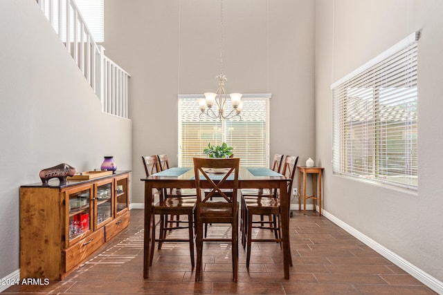 dining area featuring dark wood-type flooring, an inviting chandelier, and a towering ceiling