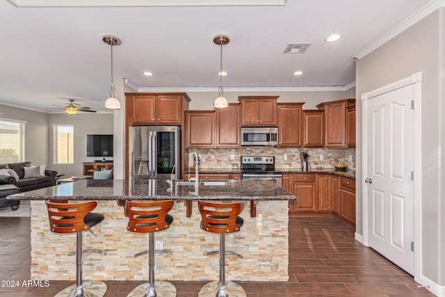 kitchen with sink, appliances with stainless steel finishes, a kitchen breakfast bar, ceiling fan, and hanging light fixtures