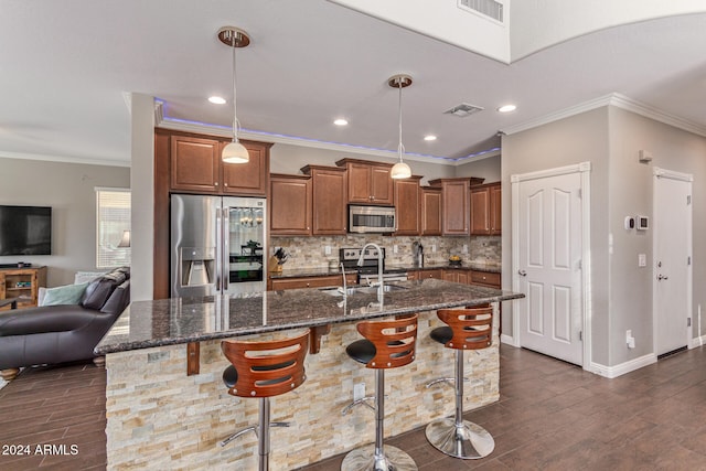 kitchen with dark wood-type flooring, a kitchen island with sink, and appliances with stainless steel finishes