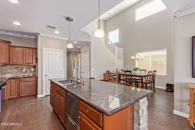 kitchen featuring sink, decorative light fixtures, an island with sink, and crown molding