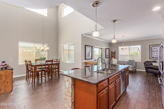 kitchen featuring a center island with sink, sink, hanging light fixtures, a towering ceiling, and dark hardwood / wood-style flooring