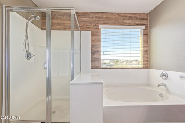 bathroom with wood walls and separate shower and tub