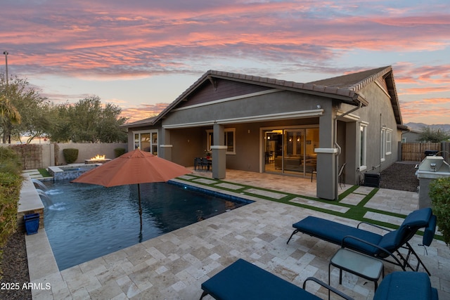 back house at dusk featuring a fenced in pool, a patio, and pool water feature