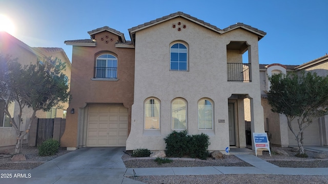 mediterranean / spanish-style home with driveway, a tiled roof, an attached garage, and stucco siding