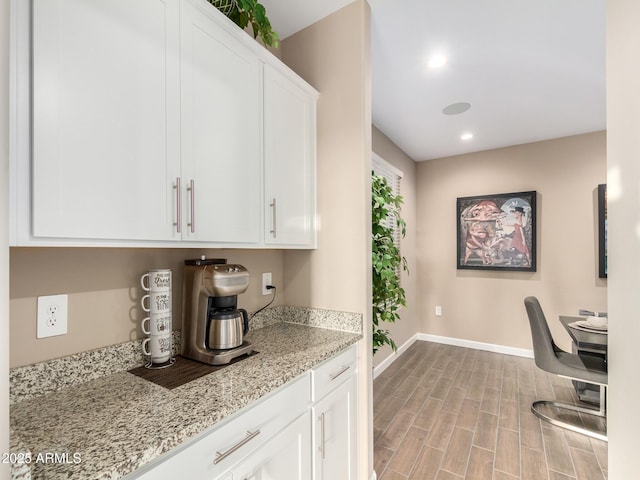 kitchen with light stone countertops, white cabinetry, and light hardwood / wood-style flooring