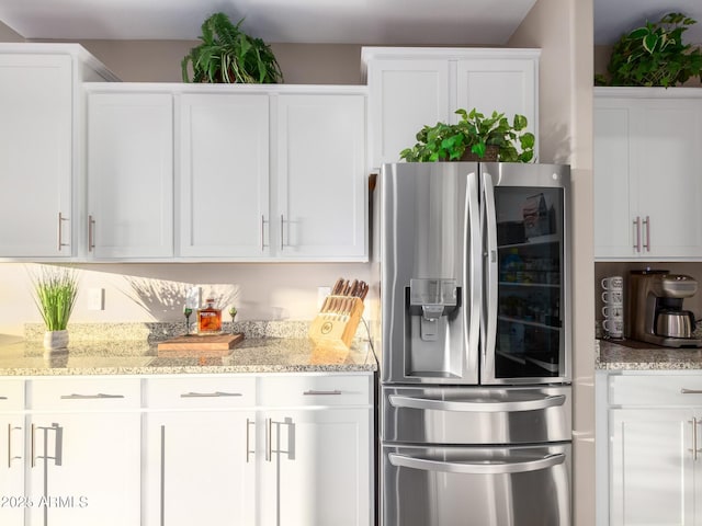 kitchen featuring stainless steel fridge with ice dispenser, white cabinets, and light stone countertops