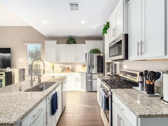 kitchen featuring a center island with sink, appliances with stainless steel finishes, white cabinetry, and sink