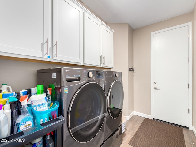 clothes washing area with washer and dryer and cabinets