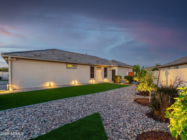 back house at dusk with a lawn