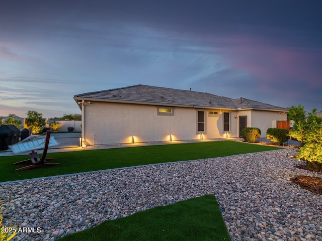 back house at dusk featuring a yard