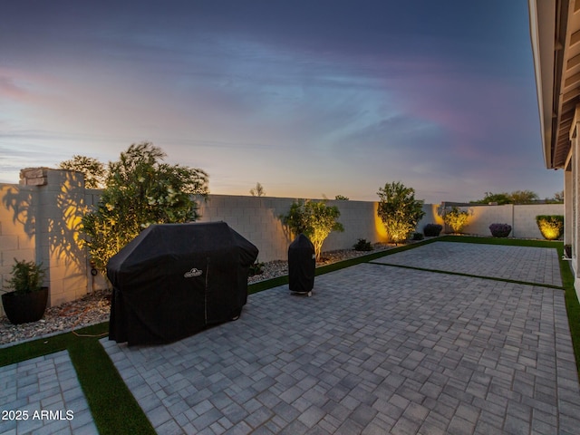 patio terrace at dusk featuring a grill