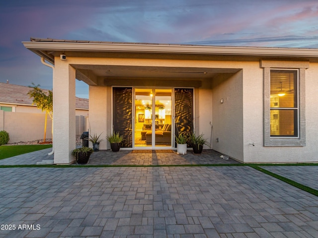 exterior entry at dusk featuring a patio