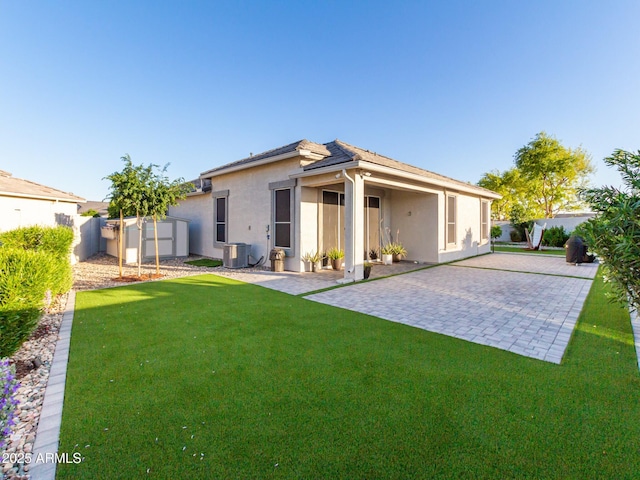 rear view of property featuring a patio area, a yard, and central AC