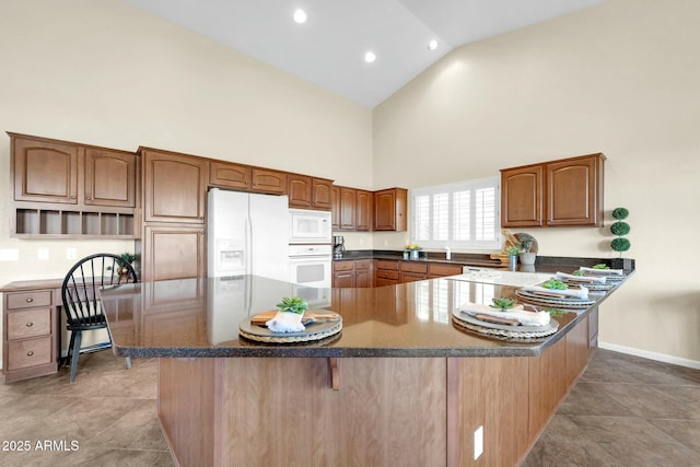 kitchen featuring a kitchen breakfast bar, high vaulted ceiling, kitchen peninsula, white appliances, and light tile patterned floors