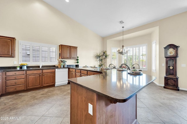 kitchen featuring light tile patterned flooring, white dishwasher, pendant lighting, and a notable chandelier