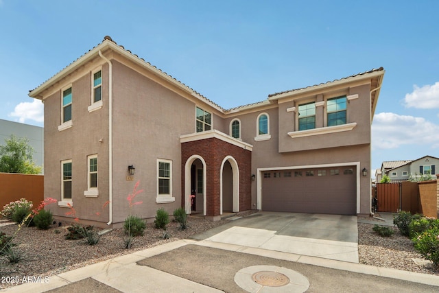 mediterranean / spanish-style house with driveway, fence, stucco siding, a garage, and a tile roof