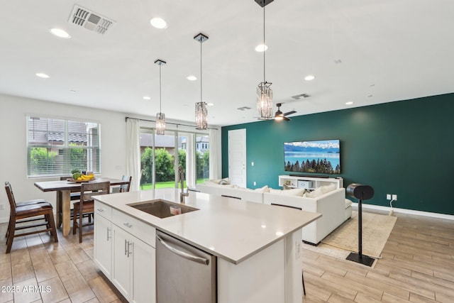 kitchen featuring stainless steel dishwasher, light wood-type flooring, recessed lighting, a center island with sink, and white cabinets