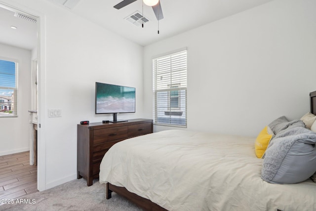bedroom featuring multiple windows, baseboards, a ceiling fan, and wood finished floors