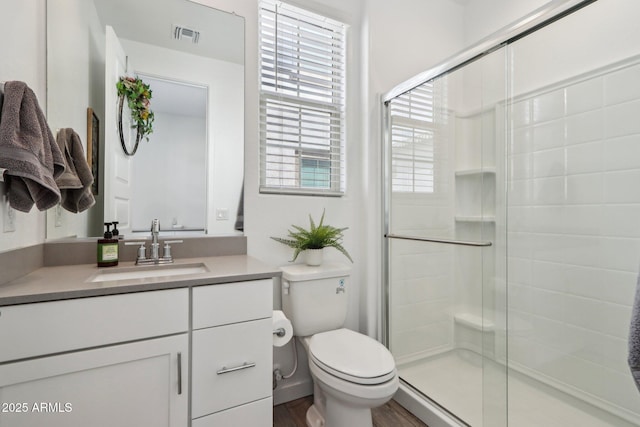 full bath featuring a stall shower, toilet, vanity, and wood finished floors
