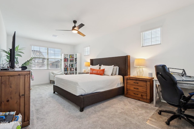 bedroom with light colored carpet, an office area, and a ceiling fan