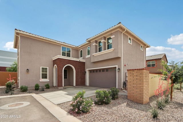 mediterranean / spanish home featuring an attached garage, concrete driveway, and stucco siding