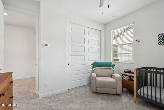 carpeted bedroom featuring a closet, a nursery area, baseboards, and ceiling fan