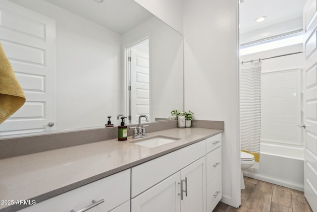 bathroom with toilet, wood finished floors, vanity, shower / tub combo, and recessed lighting