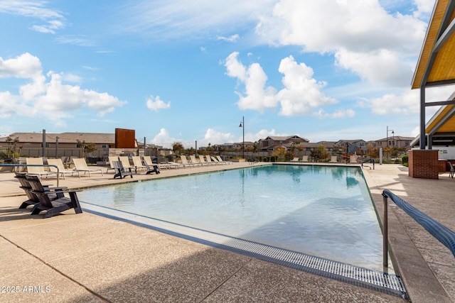 community pool featuring a patio, a residential view, and fence