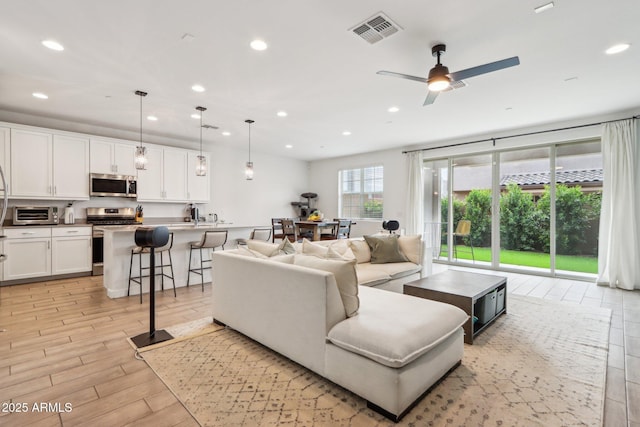 living area with recessed lighting, ceiling fan, and light wood-type flooring