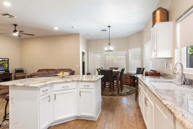 kitchen featuring white cabinetry, sink, a center island, light hardwood / wood-style flooring, and ceiling fan with notable chandelier