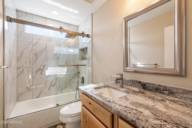 full bathroom featuring vanity, toilet, and shower / bath combination with glass door