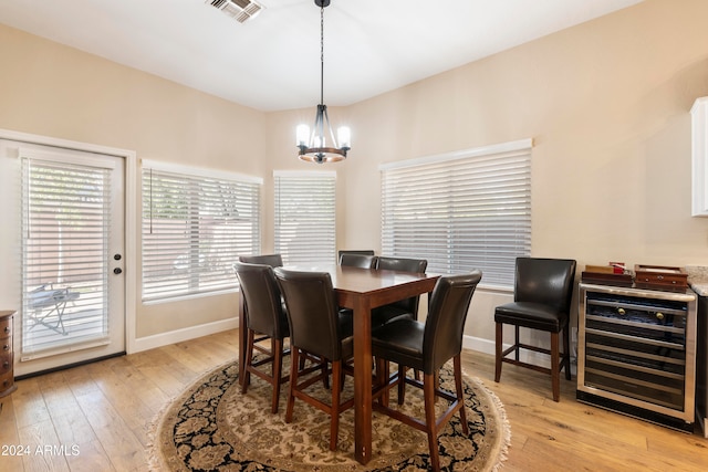 dining room featuring beverage cooler, a notable chandelier, and light wood-type flooring