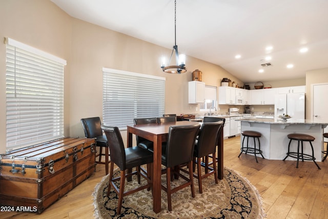 dining space featuring light wood-type flooring, an inviting chandelier, lofted ceiling, and sink