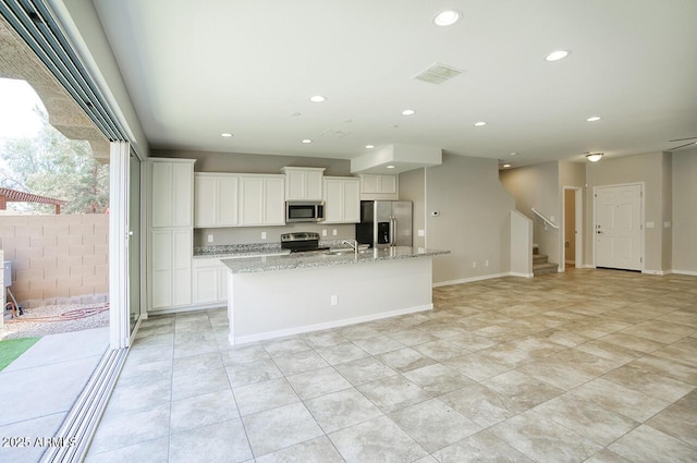 4242 E Erie St, Gilbert, AZ 85295 - kitchen with stainless steel appliances, a center island with sink, white cabinetry, recessed lighting, and light stone countertops