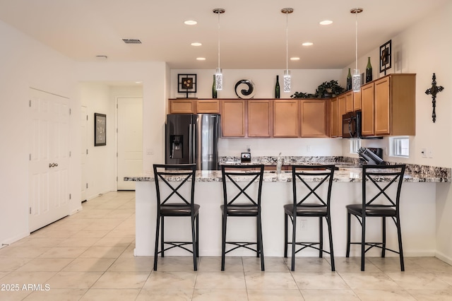 7665 W Fetlock Trl, Peoria, AZ 85383 - kitchen with fridge with ice dispenser, black microwave, a peninsula, light stone countertops, and a kitchen bar