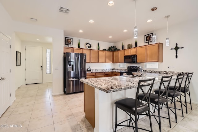 7665 W Fetlock Trl, Peoria, AZ 85383 - kitchen featuring black appliances, a peninsula, brown cabinetry, recessed lighting, and light stone counters