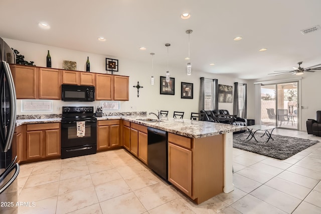 7665 W Fetlock Trl, Peoria, AZ 85383 - kitchen with black appliances, a peninsula, open floor plan, brown cabinets, and recessed lighting