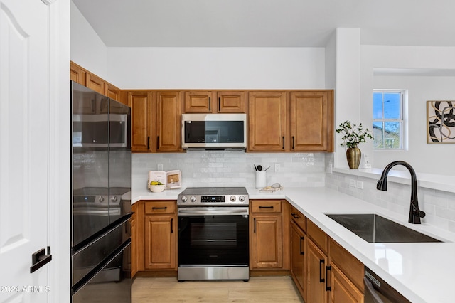 kitchen featuring decorative backsplash, appliances with stainless steel finishes, light hardwood / wood-style floors, and sink