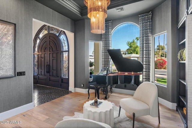 foyer featuring hardwood / wood-style flooring, crown molding, a towering ceiling, and a notable chandelier