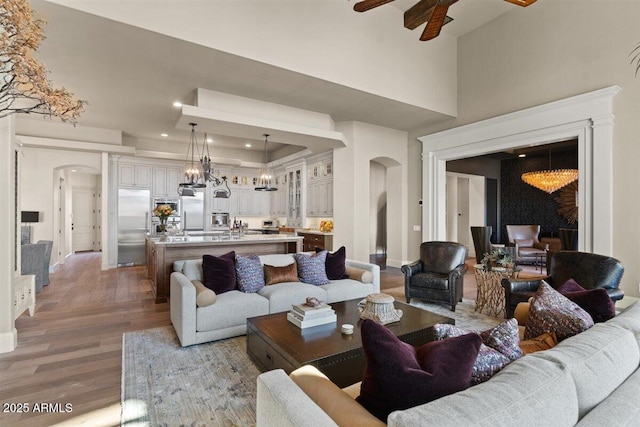 living room with wood-type flooring, a towering ceiling, and ceiling fan