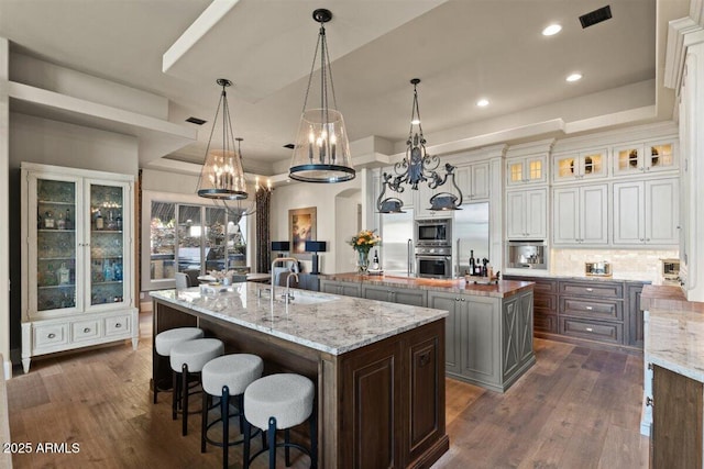 kitchen with appliances with stainless steel finishes, decorative light fixtures, tasteful backsplash, a large island, and light stone counters